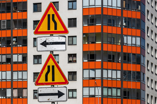 European warning road signs with arrows on the background of the facade of an apartment building with windows