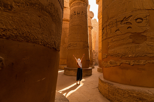 Female tourist walks between Pillars of the Great Hypostyle Hall from Karnak Temple