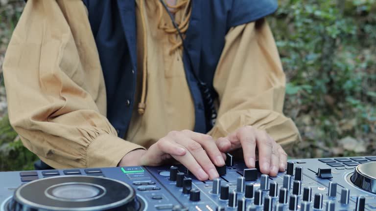 Close-up of DJ man hands playing set outdoor. Music party outside. Controling DJ sound console. Playing music at street party festival.