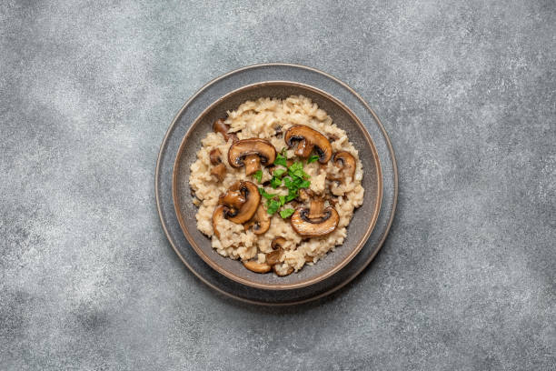 istock Risotto with brown champignons in a plate on a gray rustic background. View from above. 2149995851