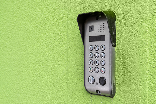Intercom with camera and keypad for access to the premises on the green wall