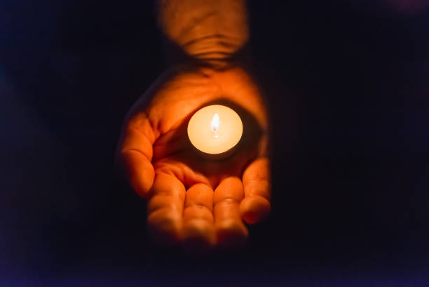 istock Burning candle in a mans hand religion concept.Candle in hands on a dark background. 2149998267