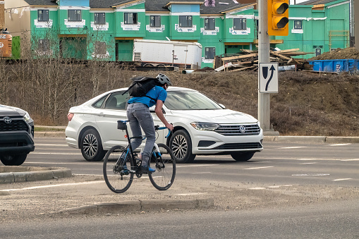 Calgary, Alberta, Canada. Apr 23, 2024. A cyclist navigating through heavy vehicular traffic on a bustling road.
