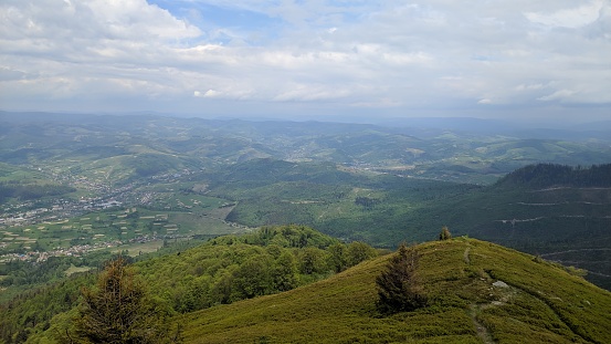 Serene View from the mountain peak of the green mountain landscape and small houses of the village conveys the calm beauty of nature. Photo.