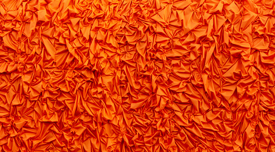 Orange silk crumpled fabric as an abstract background. Texture.