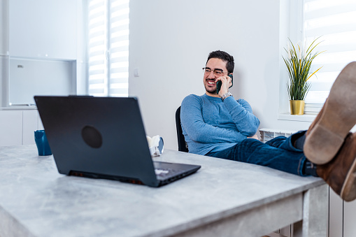 Embracing strategic downtime, a mid-adult man pauses his work to rest in his home office, understanding that maintaining peak performance often requires stepping back to recharge