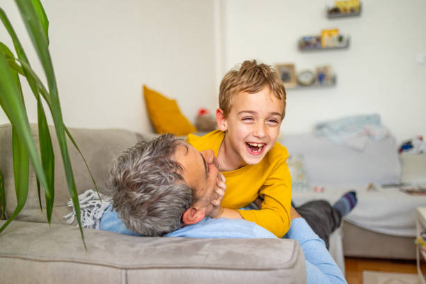 istock Portrait of father and son playing while lying on the sofa 2150003140