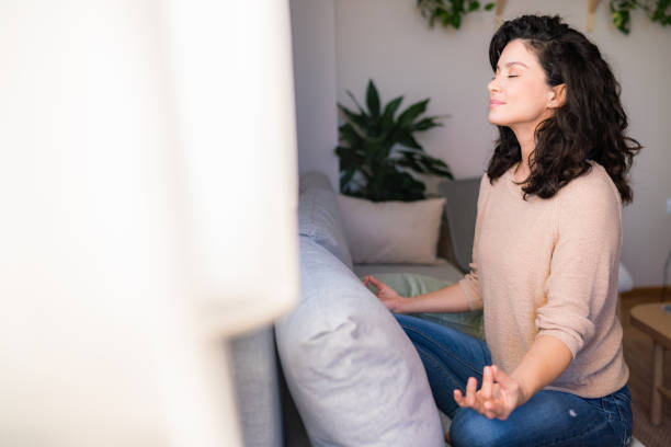 istock Woman meditating on sofa at home 2150007519