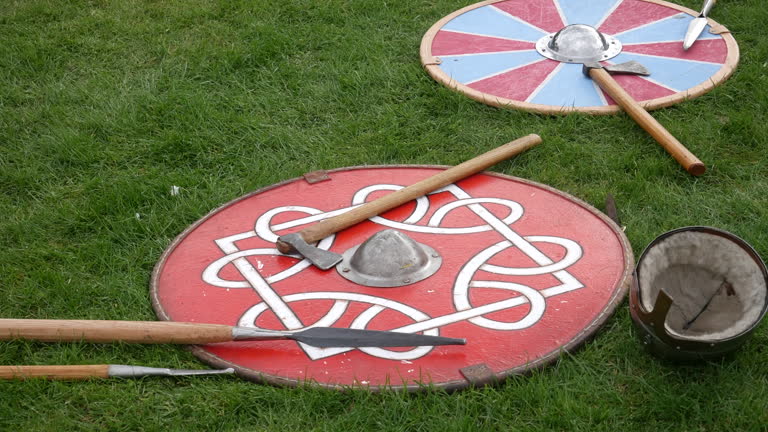 Medieval shields and weapons on grass, perfect for historical reenactment, cultural festivals, and educational use. Authentic viking replicas for period films and documentaries