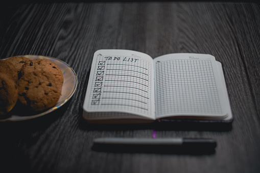 Notepad with a list of plans and a plate of cookies. High quality photo