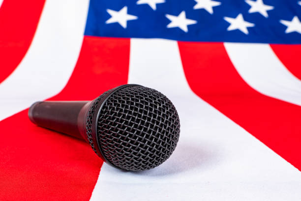 istock Microphone lies on American flag. Microphone symbolizes performance front of audience. Concept - political speeches in US. Microphone of political speaker. Pre-election meetings in America. Flag US 2150015641