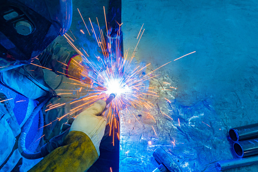 Sparks from welding. Welding production. Welder at work. A man is welding metal parts. Metalworking. Connecting metal parts.