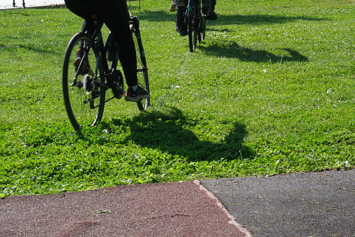 People cycling outdoors on the weekend. People cycling on the bike path among grass and flowers