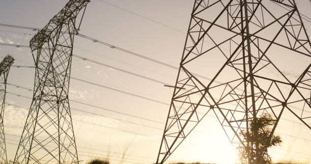 istock Transmission, tower and electricity lines or engineering cables for power voltage, infrastructure or steel. Sunset, pylon and pole connection with blue sky or circuit current, industrial or structure 2150016614
