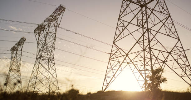 istock Transmission, tower and electricity lines or industrial engineering for power voltage, infrastructure or steel. Sunset, pylon and pole or grid cables with blue sky or circuit, current or connection 2150016615