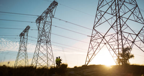 istock People, engineering and transmission tower or sunset for electricity maintenance, teamwork or circuit. Blue sky, inspection and pylon pole for power supply or steel grid, industrial or infrastructure 2150016904