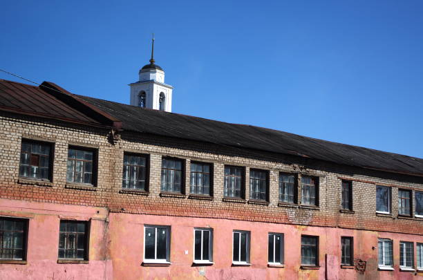 istock An old two-story brick Soviet building with a bell tower in background a rural area, clear blue sky, sunny day 2150017375