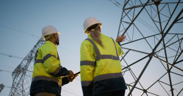 istock People, electrical engineer and tablet in power plant with inspection for electricity transmission and tower check. Engineering, collaboration and data transfer for energy distribution and low angle 2150017405