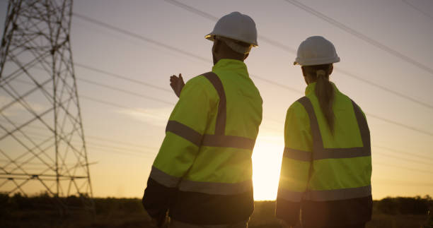 istock Teamwork, electrical engineer and engineering in power station with sunset for electricity inspection and tower check. Construction, rear view and collaboration for energy distribution and discussion 2150017409
