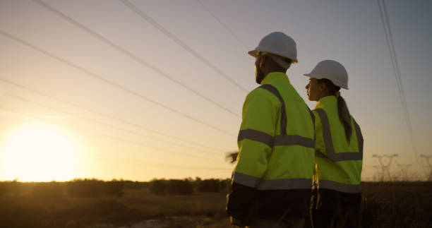 istock Teamwork, electrical engineer and construction in power station with sunset for electricity inspection and tower check. Engineering, rear view or collaboration for energy distribution and maintenance 2150017412