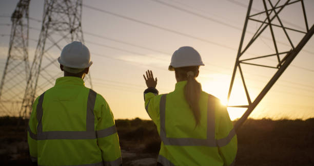istock Teamwork, electrical engineer and construction in power plant with sunset for electricity inspection and tower check. Engineering, rear view and collaboration for energy distribution and maintenance 2150017414