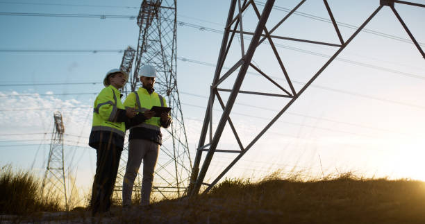 istock People, electrical engineer and tablet in power station with sunset for electricity transmission system or tower check. Engineering, inspection or collaboration for energy distribution or maintenance 2150017418