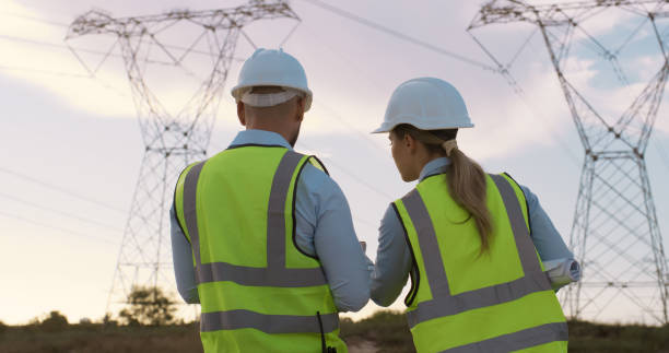 istock Teamwork, electrical engineer and engineering in power station with talking for electricity inspection and tower check. Construction, rear view or collaboration for energy distribution or maintenance 2150017427