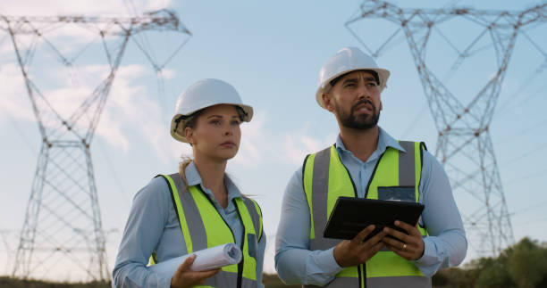 istock Teamwork, electrical engineer and construction in power plant with tablet for electricity inspection and tower check. Engineering, troubleshoot or collaboration for energy distribution or maintenance 2150017431