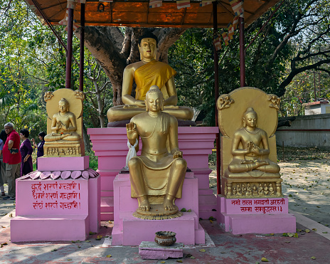 Sarnath, Uttar Pradesh, India - March 22nd, 2024: Golden statues of sitting Buddha outside Thai temple in Sarnath near Varanasi. Text in local language are mantras.