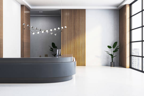 istock Modern office reception area with desk, decorative lighting, wooden panels, plants, and a large window. Light and clean design. 3D Rendering 2150017671