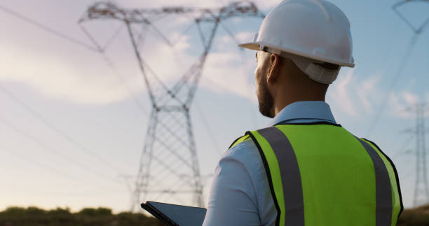 istock Back, tablet and man with power construction, outdoor and electric engineering with internet, safety or digital app. Person, employee or consultant in field, tech or inspection for high voltage tower 2150018089
