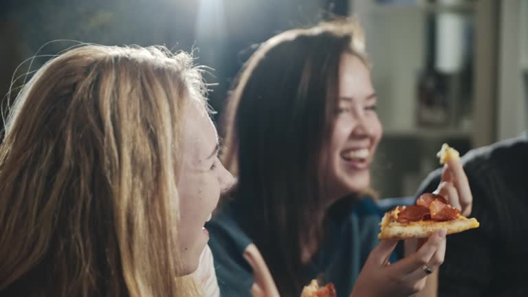 Everybody laughing, chatting having great time together. Happy group of friends sharing pizza. One girl stealing piece from friend. Concept of millenials, lifestyle, indoors leisure, food.