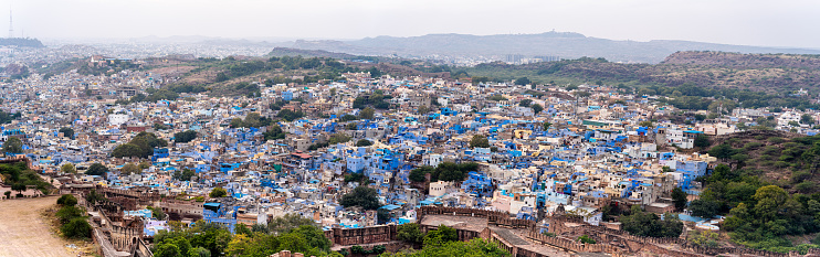 Panoramicaerial drone shot showing jodhpur blue city cityscape showing traditional houses in middle of aravalli with colorful densely packed houses India