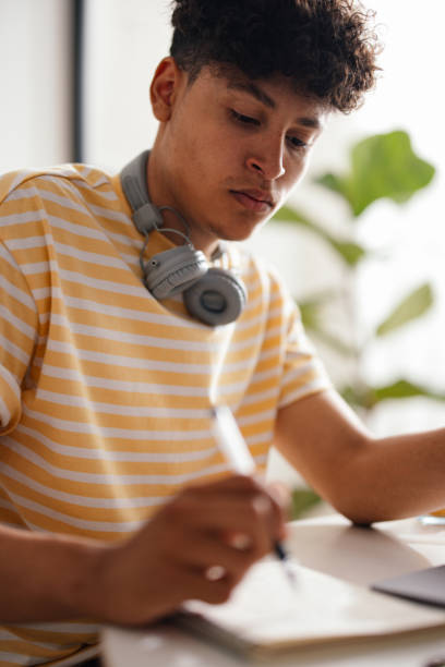 istock Focused Teenager Studying Hard at a Bright Home Desk 2150019599