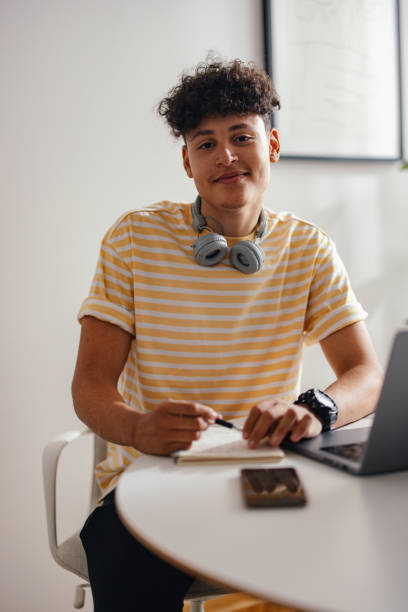 istock Young Man Studying at Home with Notebook and Laptop 2150019621