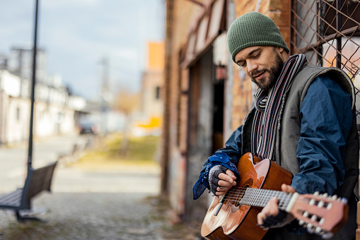 Man Beggar Living in Poverty Playing the Guitar to Sing a Song on the Street. Homelessness Social Issues Concept.