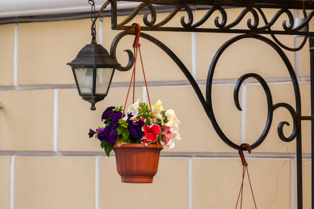 A hanging flower pot and lantern against a brick wall backdrop.