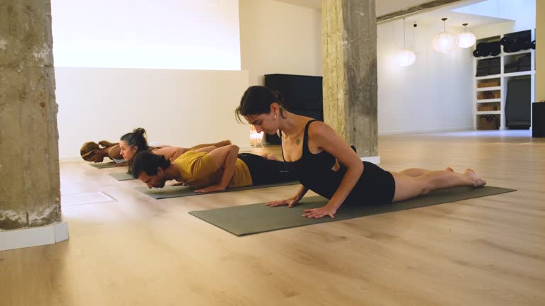 Four people bending over to unroll the mat before the yoga class.