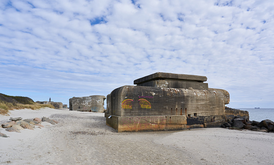 Skagen, Denmark. April 18, 2020. Old ruined Atlantic wall bunkers on sandy beach at seashore against white cloudy sky at Løkken, Jutland, Denmark