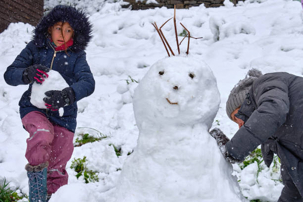 istock Mother and daughter building snowman 2150022508