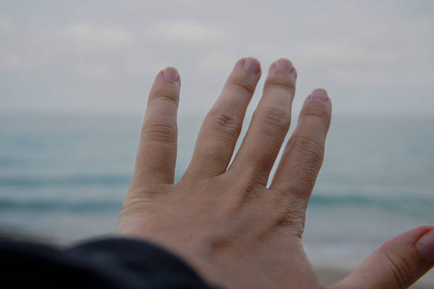 Hand reaching out to the sea from a beach