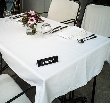 reserved white table with flowers and white tablecloth