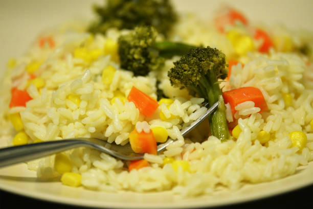 High angle view of delicious cooked rice ready to eat over white plate in the kitchen at home on rustic wood table.