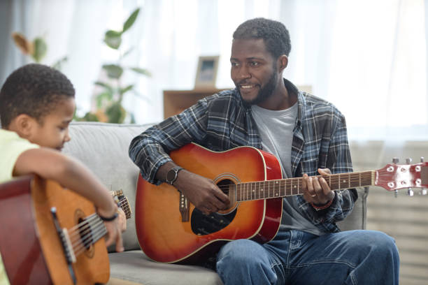 istock Smiling Black Man with Son Playing Guitar 2150029156