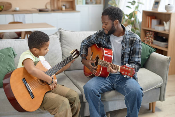 istock Black Boy Playing Acoustic Guitar with Dad 2150029165