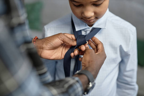 Black father tying tie for son Close up of loving African American father tying tie for son first day of school child tied up stock pictures, royalty-free photos & images