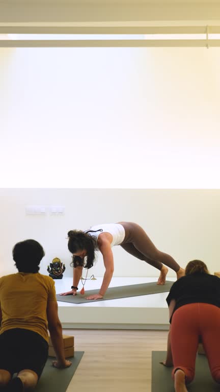 Three people are practicing upward and downward dog yoga on mats in a class.