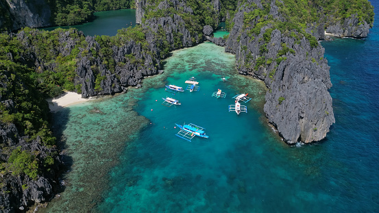 Aerial view of tropical island in Philippines. Boats in blue lagoons and lakes, rocks cliffs reef
