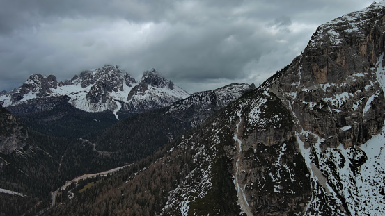 Aerial view of amazing rocky mountains in snow under moody gray clouds, Dolomites, Italy