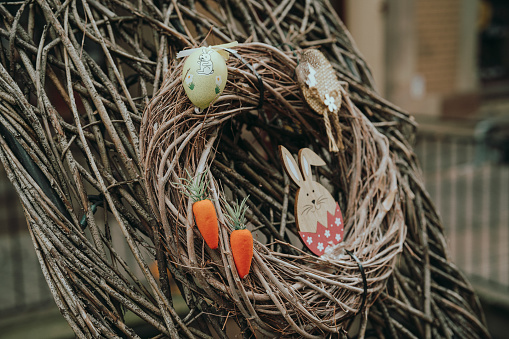 Close-up of a handcrafted Easter wreath adorned with eggs, a wooden bunny, and felt carrots, capturing the spirit of the holiday.